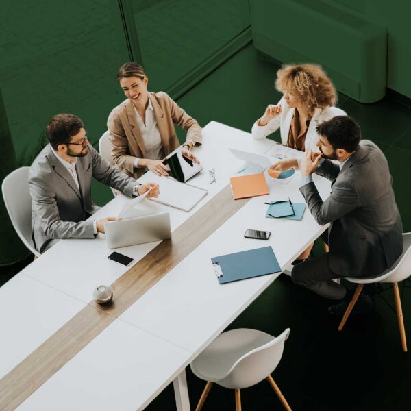 Business professionals collaborating during a team meeting around a conference table with laptops and documents.