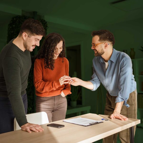 Real estate agent handing house keys to happy homebuyers after completing the home purchase process.
